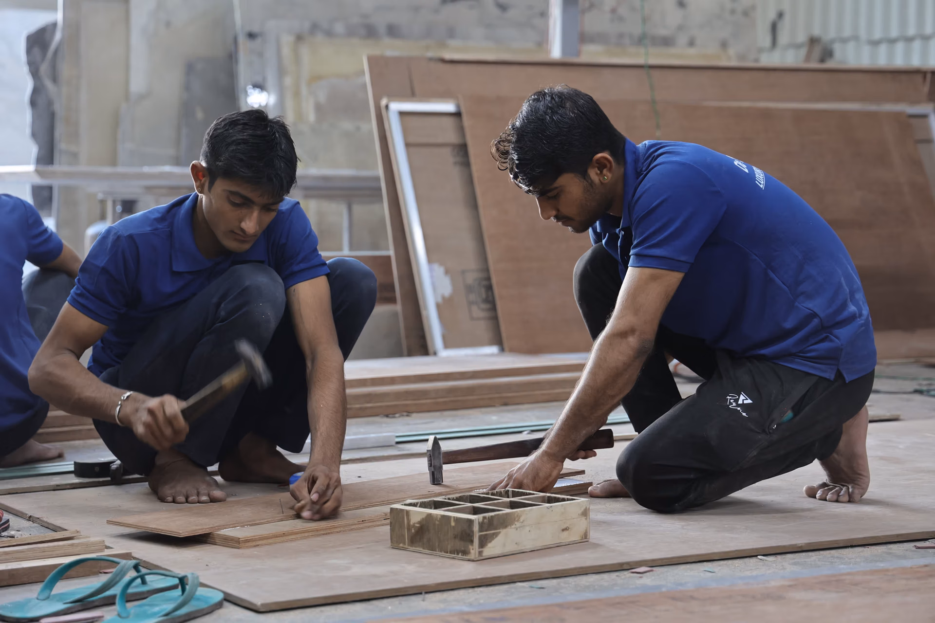 Craftsmen building bespoke furniture inside a large, organised furniture workshop.
