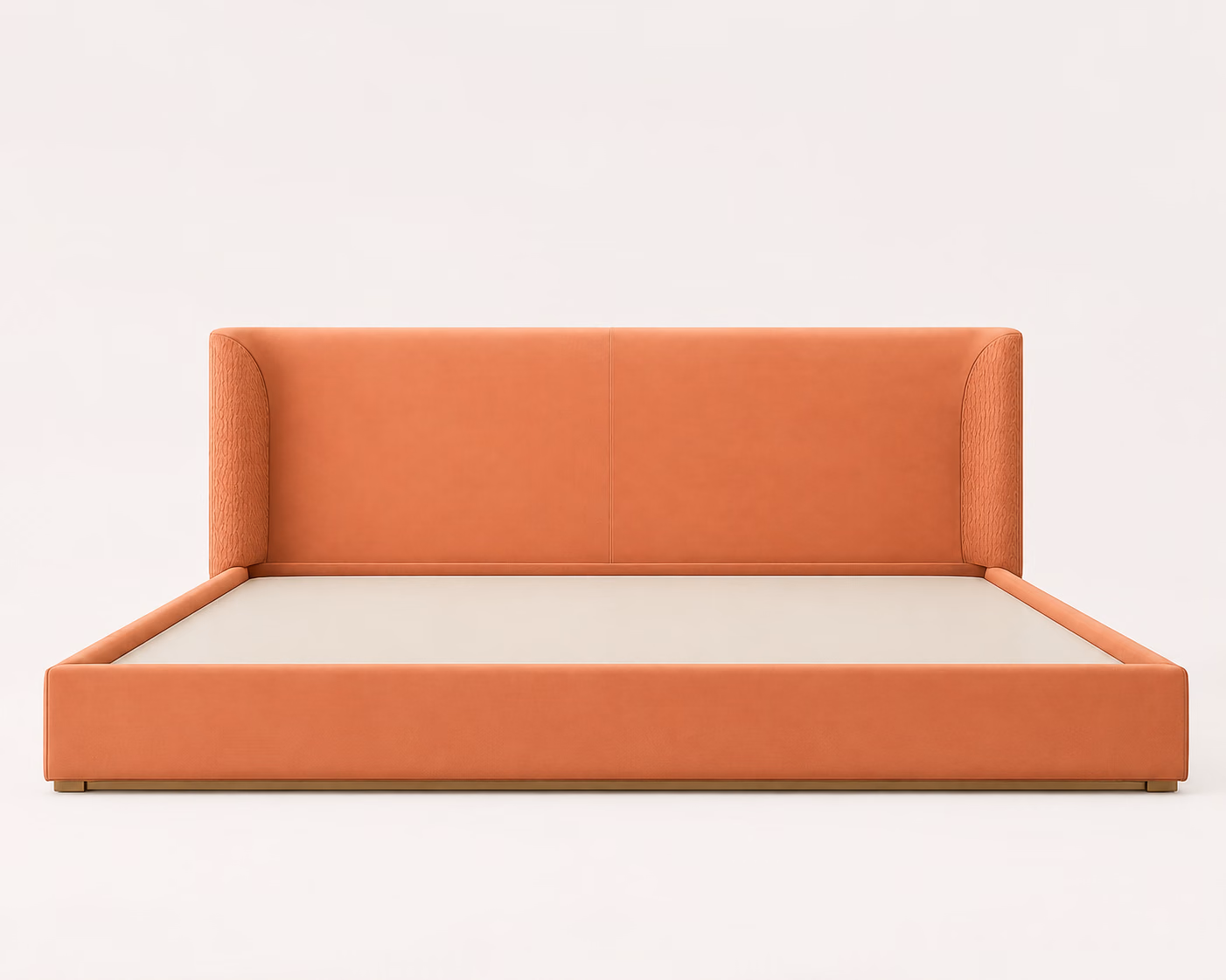 Designatore platform bed upholstered in smooth terracotta leather with quilted wings on the headboard, a fully upholstered frame and a low champagne metal base, shown alone on a bone-white ground.