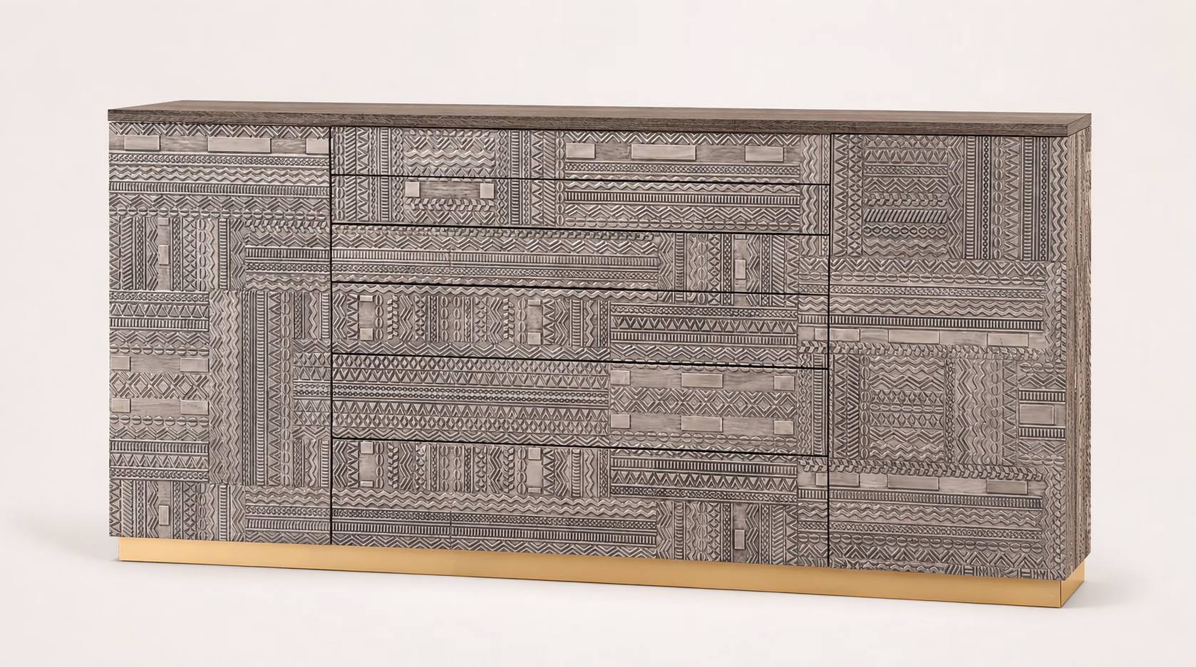 Designatore console chest shown alone, its whole front covered in hand-carved geometric patterns in a rich grey-brown wood, with slim recessed metal drawer pulls and a brushed gold plinth base.