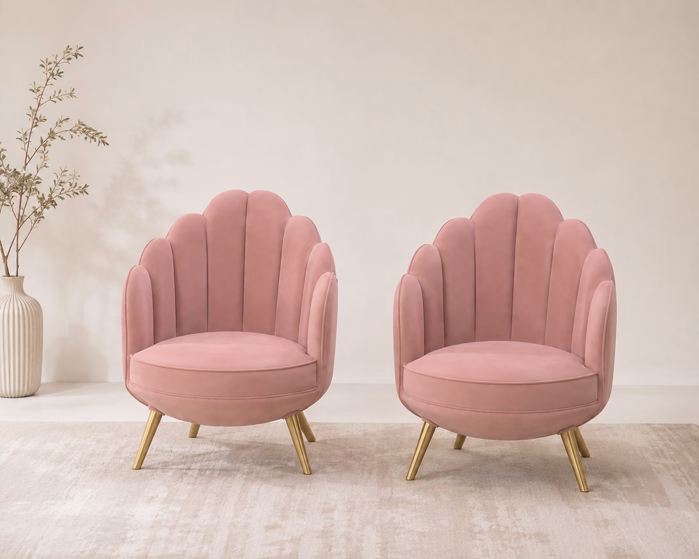 Designatore accent chair shown alone on a bone-white ground, upholstered in blush pink velvet with a scalloped shell-shaped back, curved integrated arms, a plush round seat cushion and splayed brushed gold metal legs.