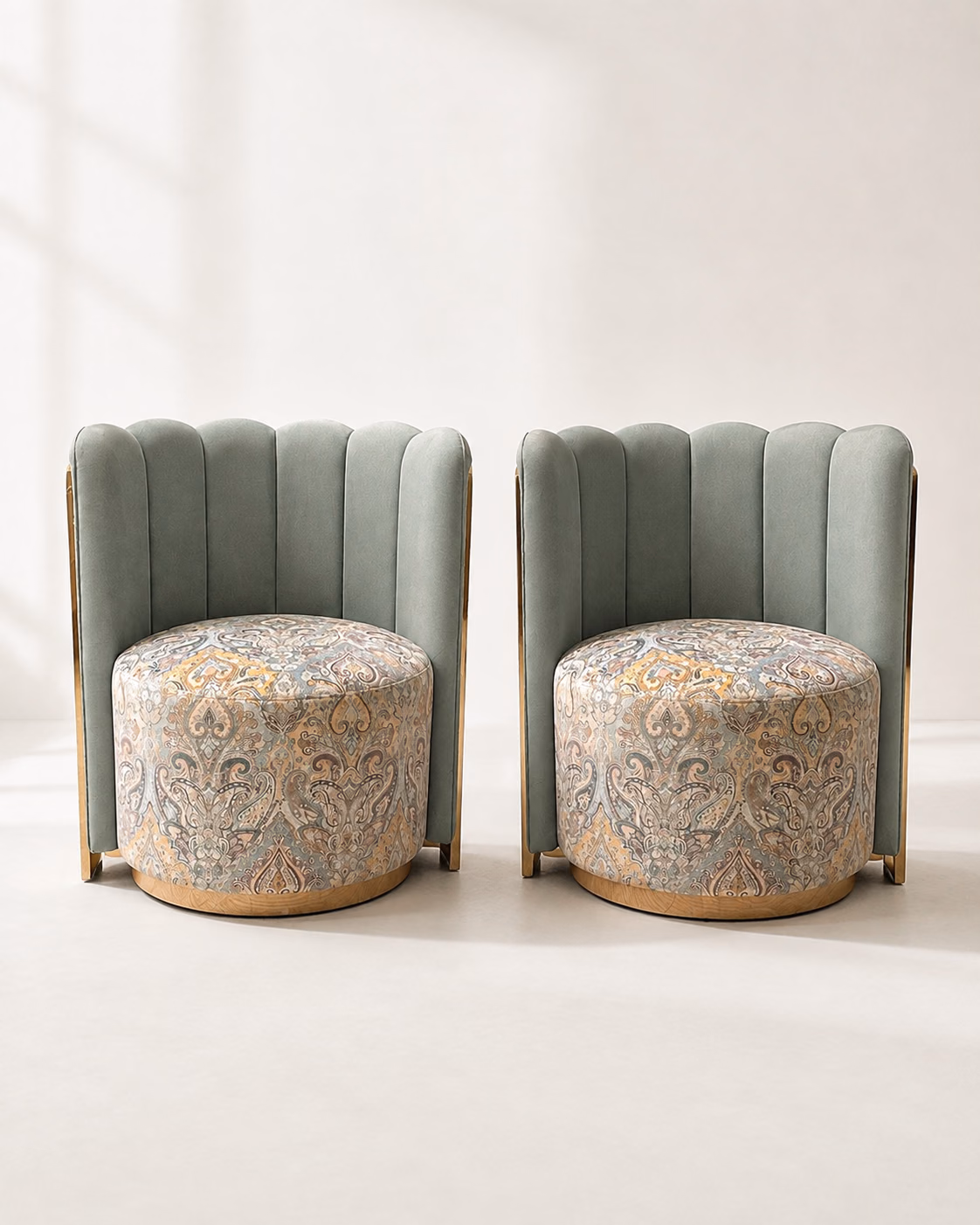 Designatore barrel chair shown alone on a bone ground, with a channel-tufted sage green velvet back, a round seat upholstered in a grey and gold paisley printed fabric, polished gold metal accents down the sides and a solid ash wood base ring.